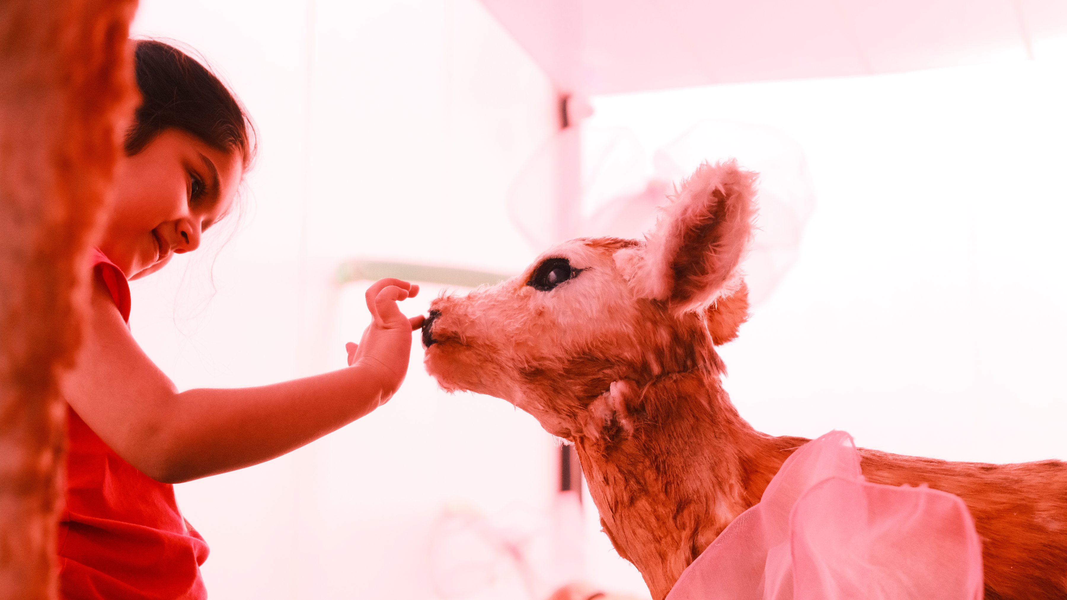 A girl leaning in close to a fawn sculpture’s nose