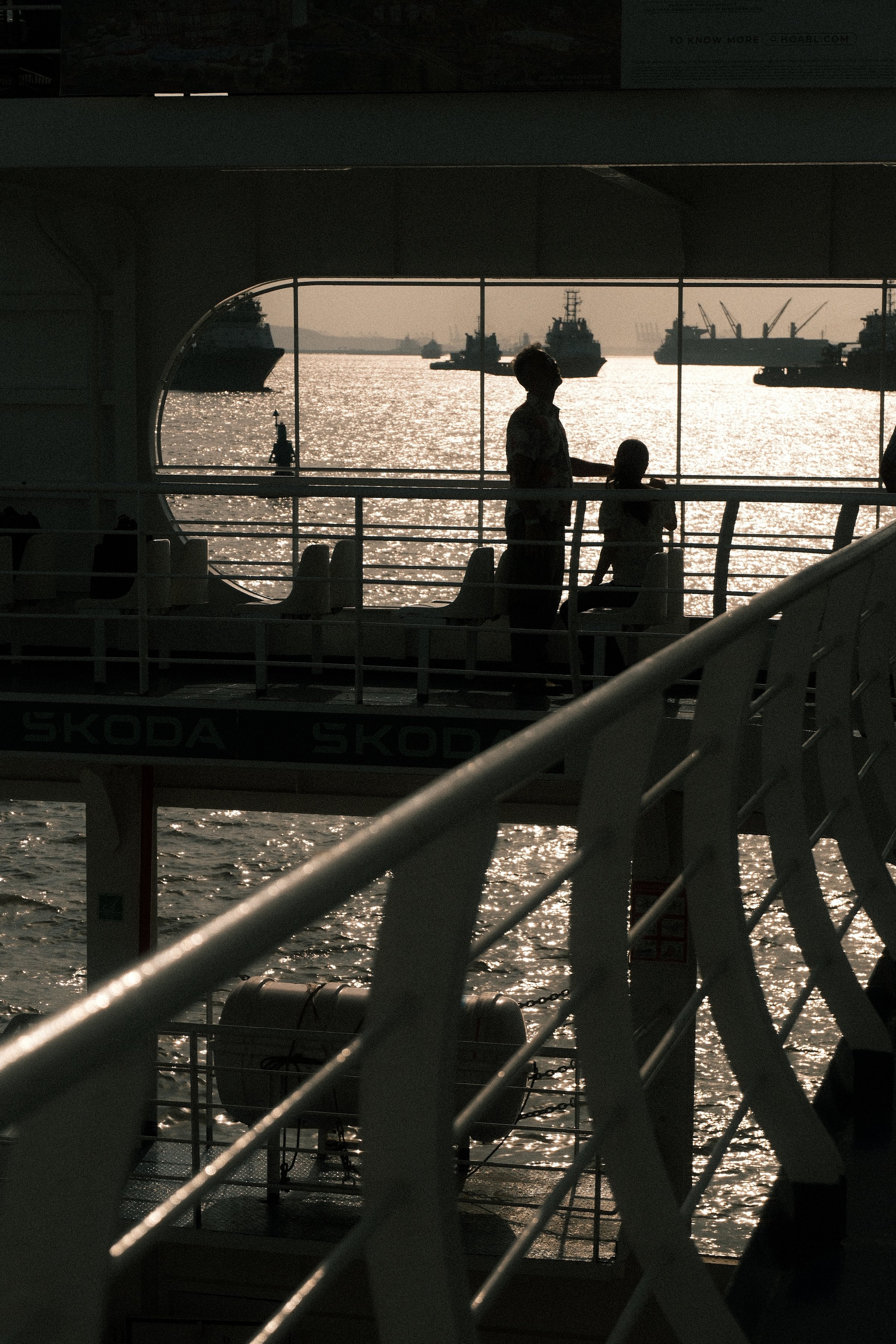 Silhouettes at a ferry window above glittering water