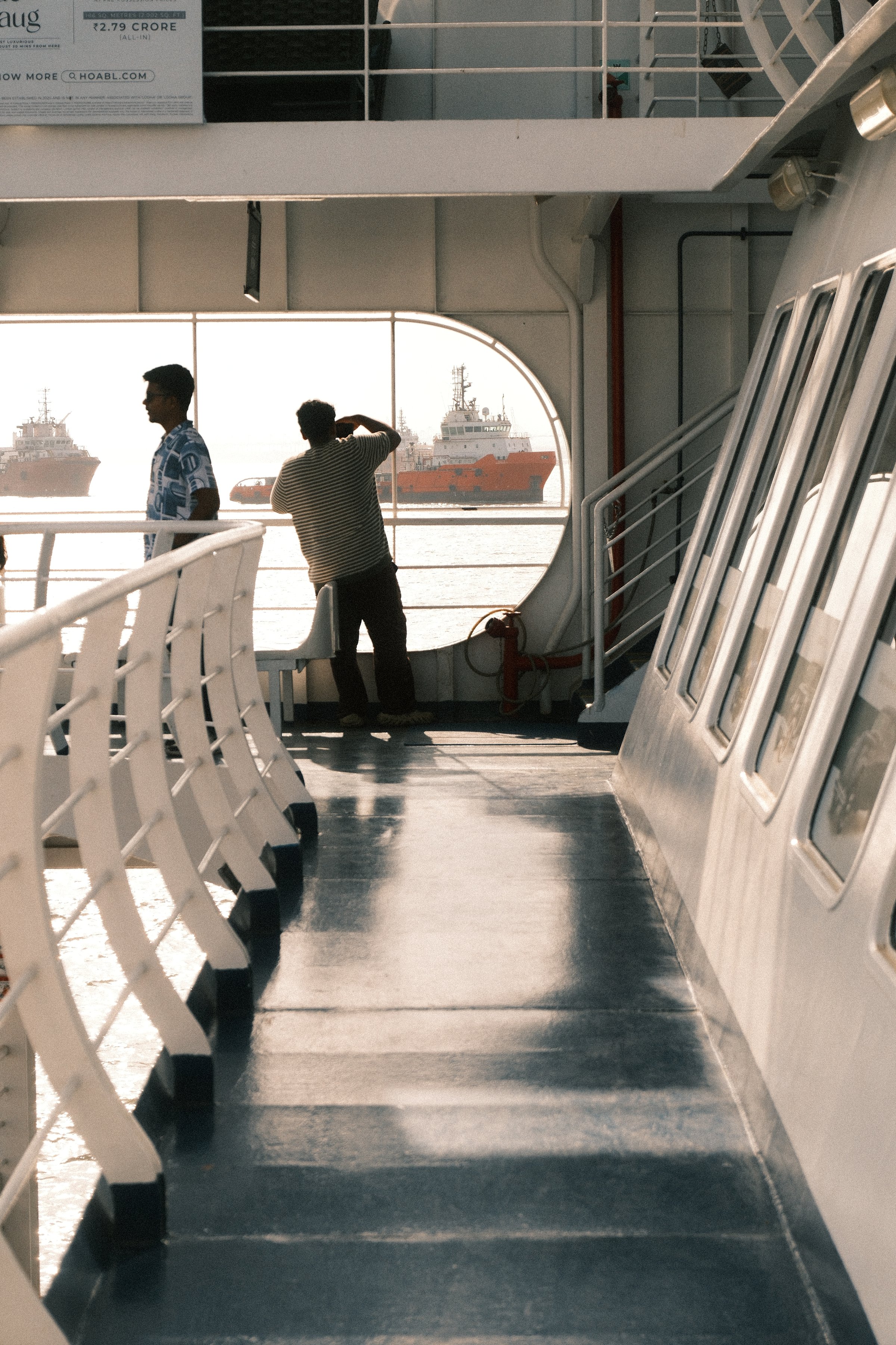 Two people at the rail of a ferry looking out at ships