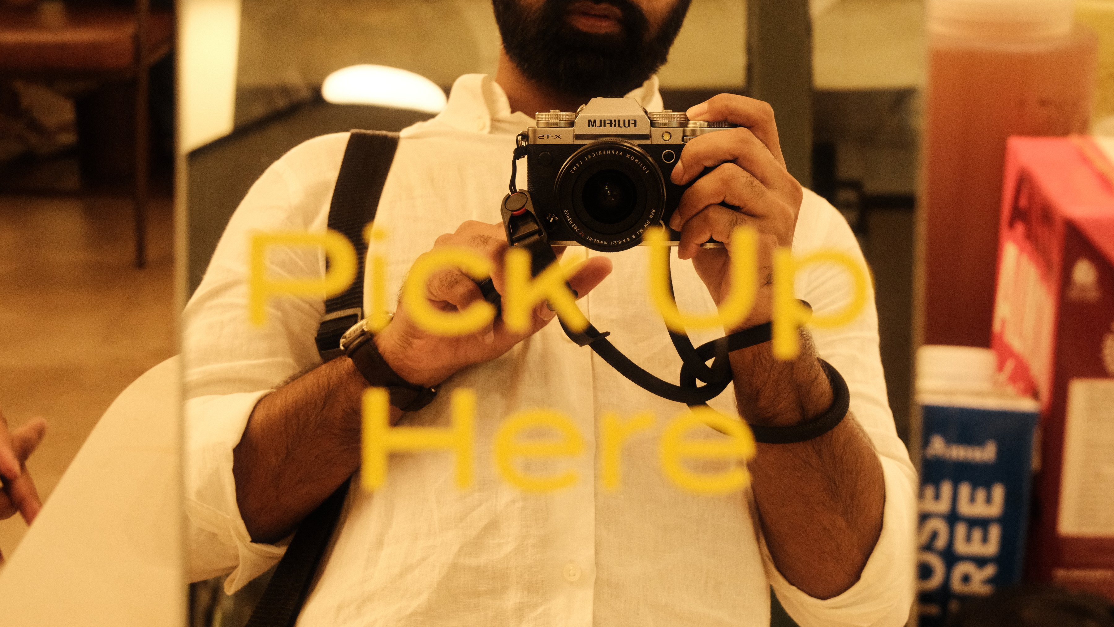 The photographer reflected in a mirror behind a sign reading Pick Up Here