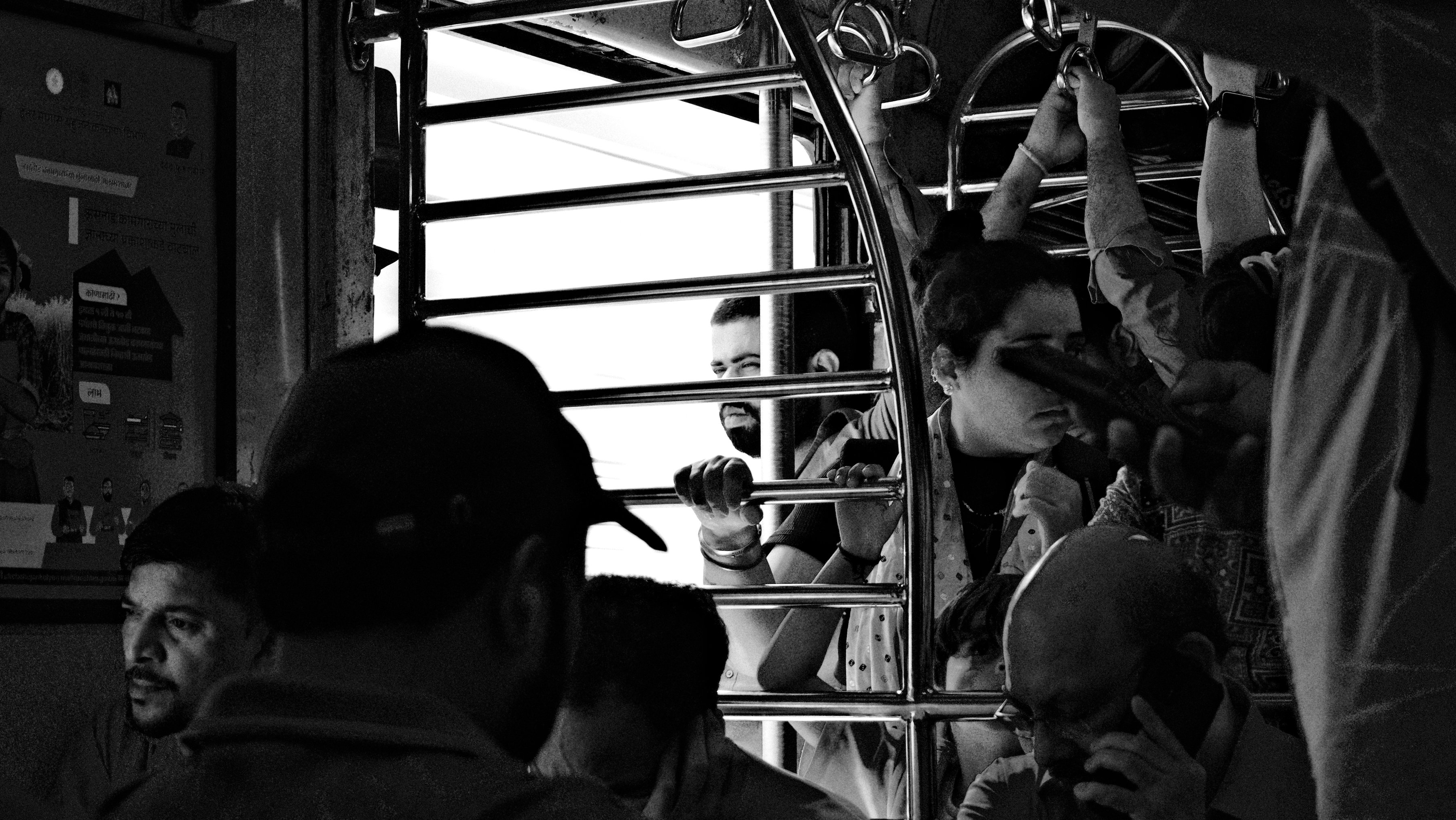 Commuters crowded at the open door of a local train, in black and white