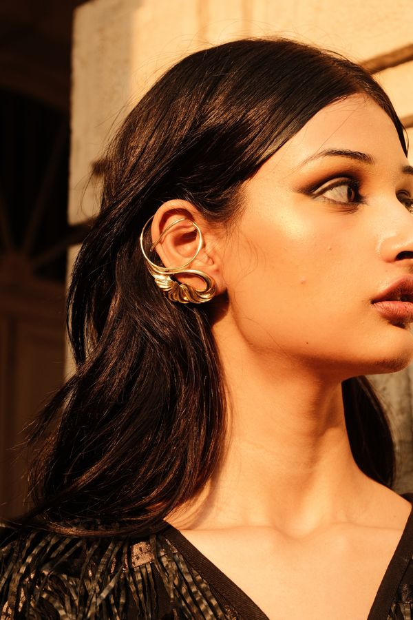 Close profile portrait of a model wearing a gold ear cuff