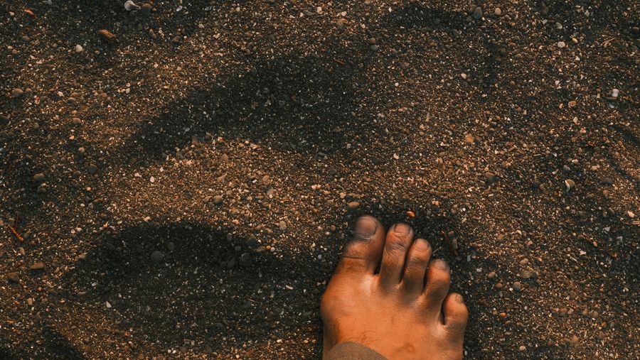 A bare foot pressing into dark sand