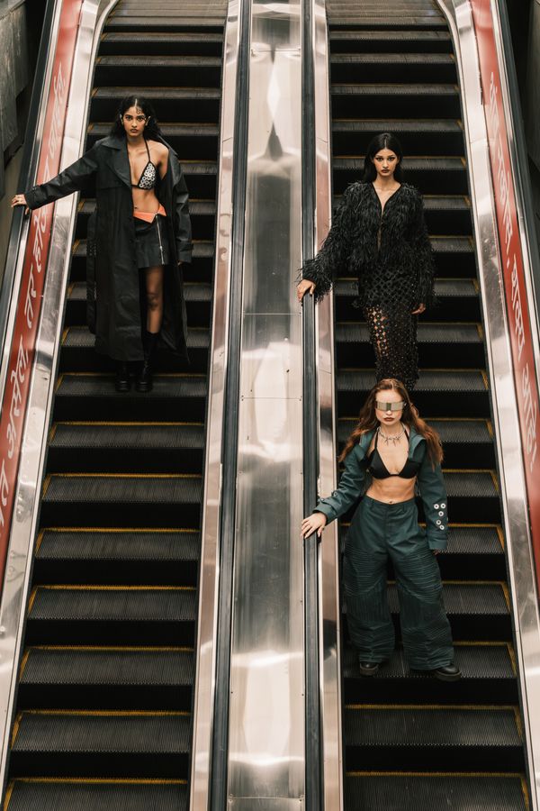 Three models standing one behind another down the escalator