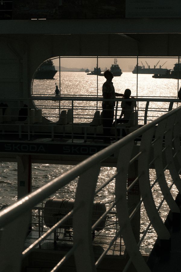 Silhouettes at a ferry window above glittering water