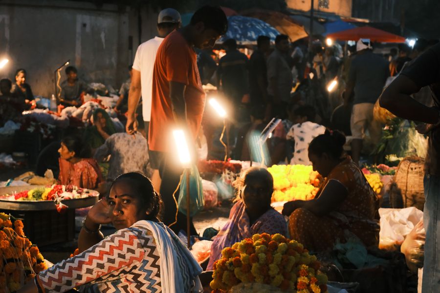 Women sorting heaps of marigolds by lamplight