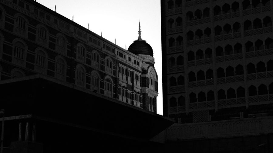 A domed heritage hotel half in deep shadow, in black and white