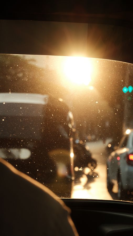 Low sun flaring through a taxi windshield in evening traffic