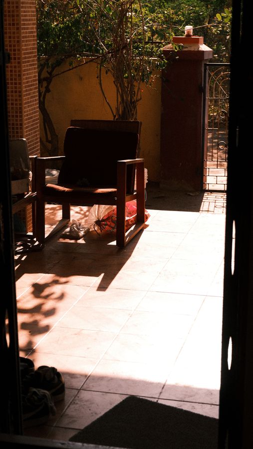 A lone chair in a sunlit courtyard seen through a dark doorway