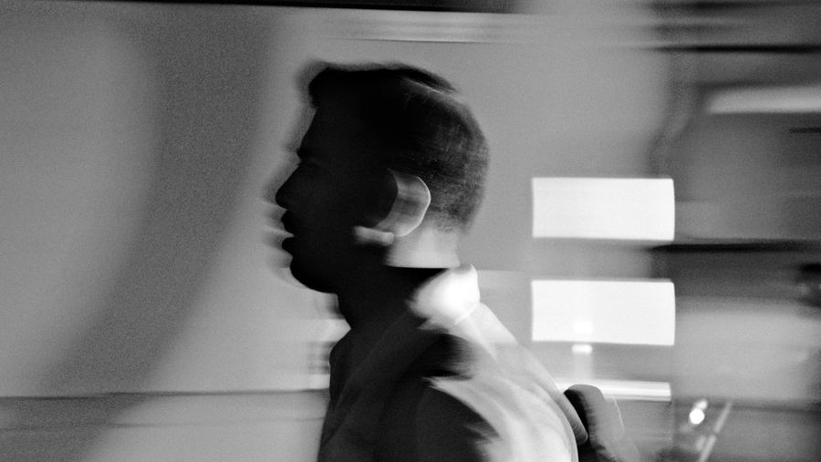 A man moving past a bright window, blurred, in black and white