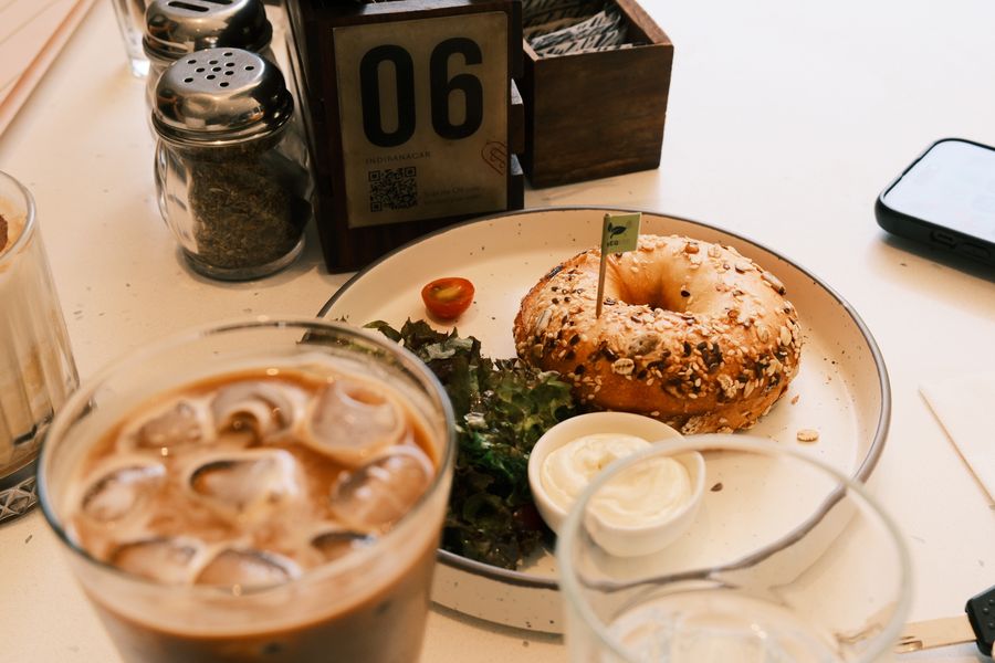 A bagel, salad and an iced coffee on a café table beside a table number