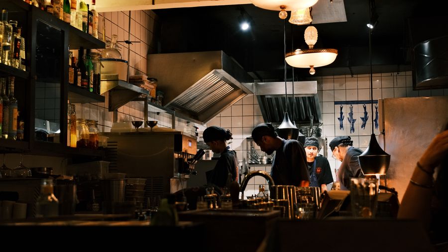 Chefs at work behind the counter of a busy open kitchen at night