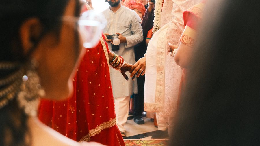 The couple’s hands meeting during the ceremony as guests look on